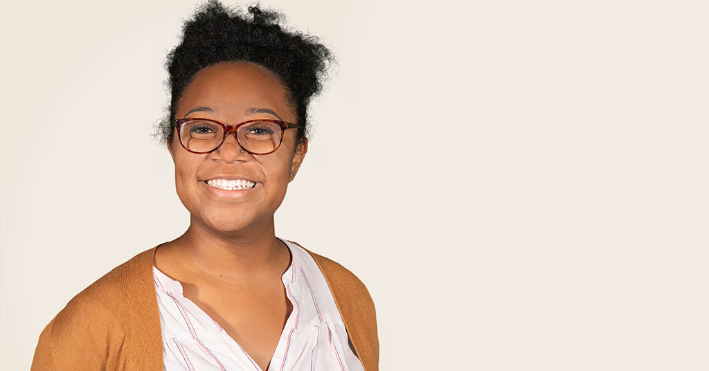 Khaniya Russell, a Charles Butt Scholar Alumni, smiles in front of a cream colored backdrop