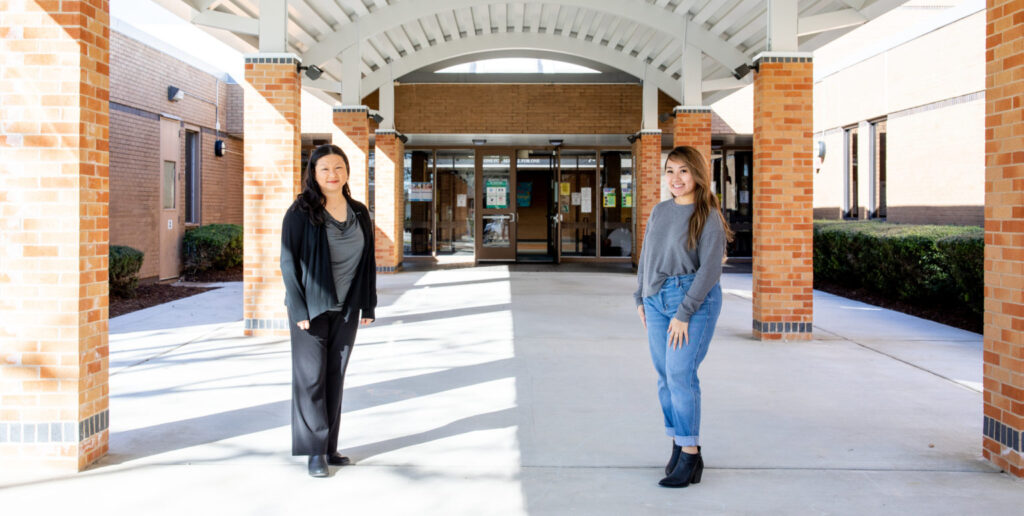 A principal and a young lady who is a former student and now an aspiring teacher stand outside the front of Martin Elementary School.