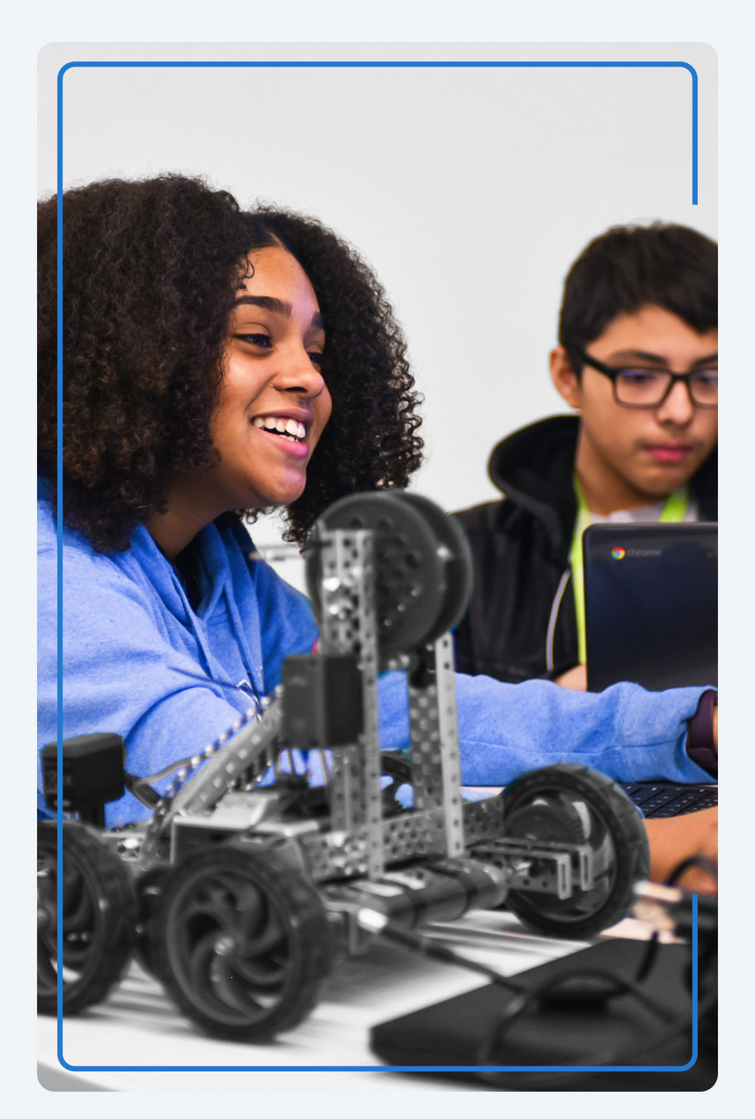 CAST Network student in robotics class is seen smiling while chatting with a peer.