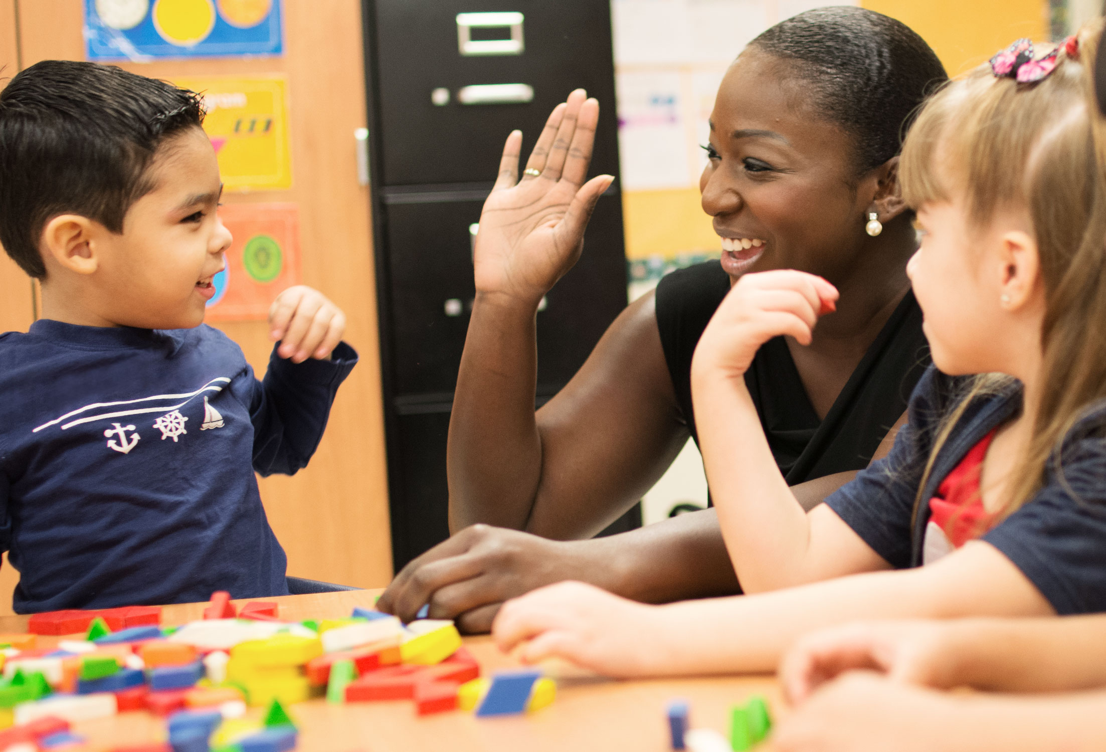 Diverse assistant principal giving high five to elementary school students
