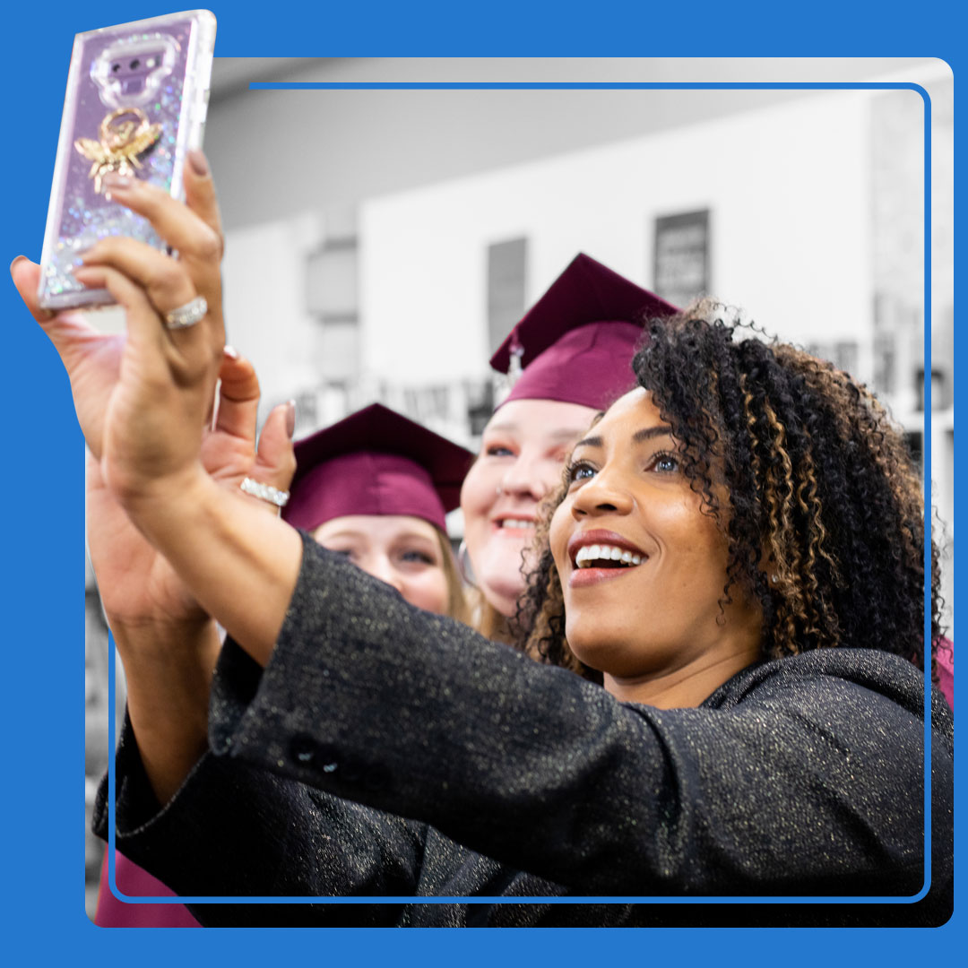Principal takes a selfie with high school graduate at a PACE graduation ceremony.