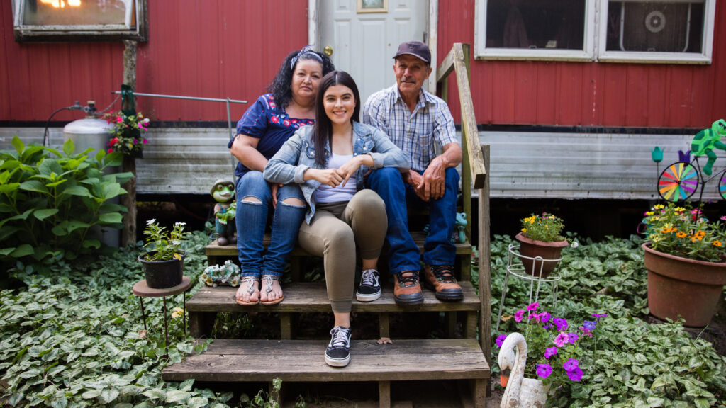 La familia Pérez sentada en las escaleras afuera de su casa móvil en Benton Harbor Michigan