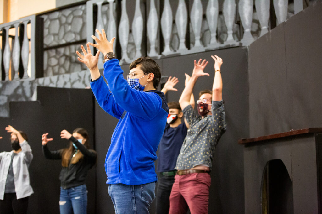 Theatre students engage in a vocal warm up activity on stage.