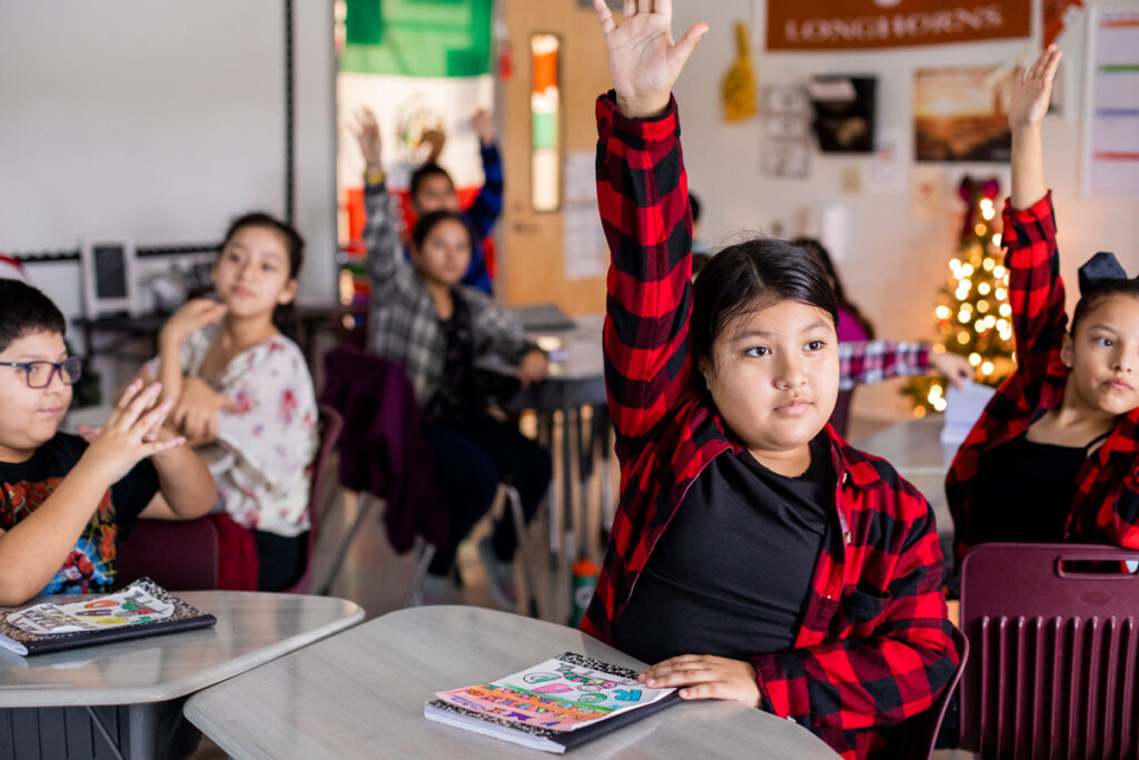 A student in Uriel Iglesias' fourth-grade bilingual classroom raises her hand to offer an answer to the reading lessons.