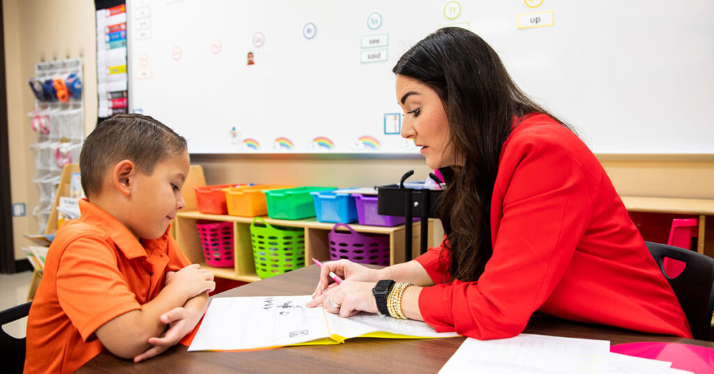 A kindergarten teacher works one-on-one with a student.