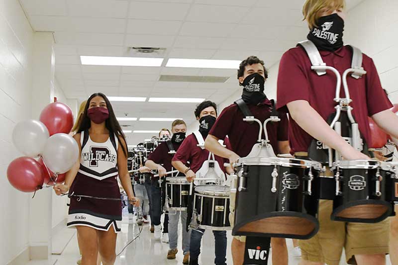 The high school drum line marches through the halls of the school. They are masked for safety.