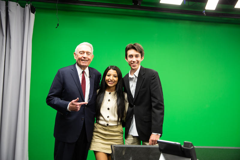 Dan Rather poses for a photo with two student news anchors at Heights High School