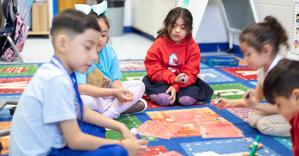 Kindergarten students work together on a small-group activity sounding out letter sounds.