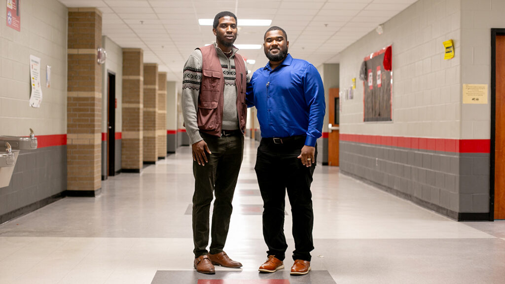 Brothers Jeffrey Rogers and LaDerrington Bradford pose together in a hallway at Cleveland High School where they both teach.