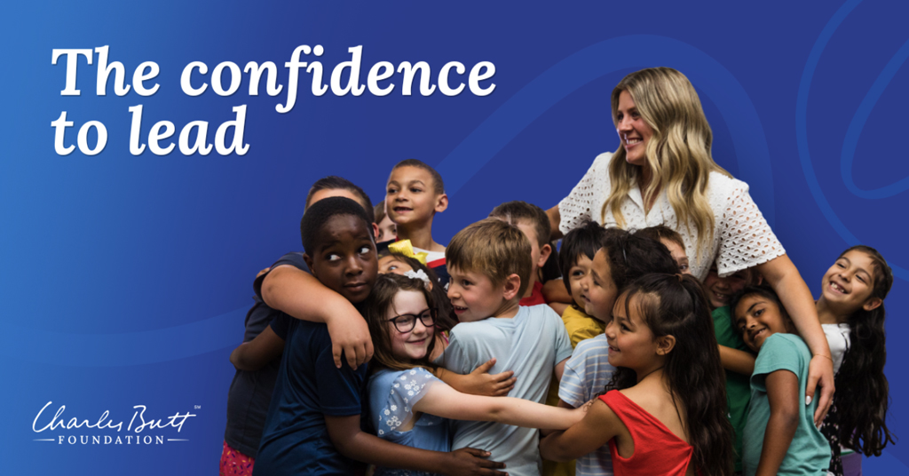 Lydia Sewell stands at the front of her class while being embraces by her students. The words "The confidence to lead" appears next to Lydia.